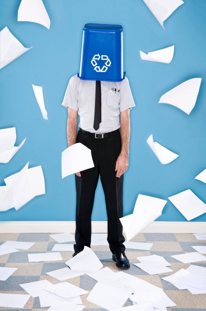 A paper recycling bin on a person's head with paper floating around them
