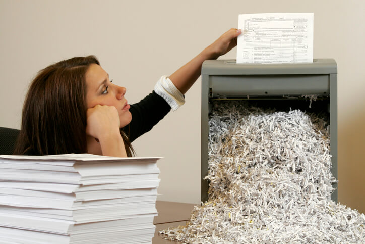 A woman putting many documents through an office shredder