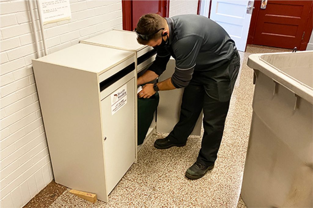 Security Shredding employee emptying a residential shredding console bin