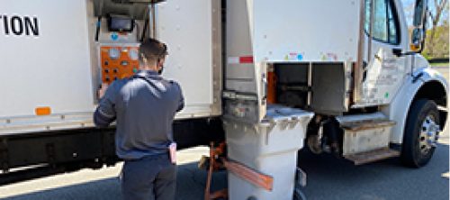 Security Shredding employee loading a shred bin onto shred truck
