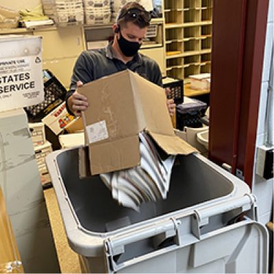 Security Shredding employee emptying a box of shredding paper into a shred bin