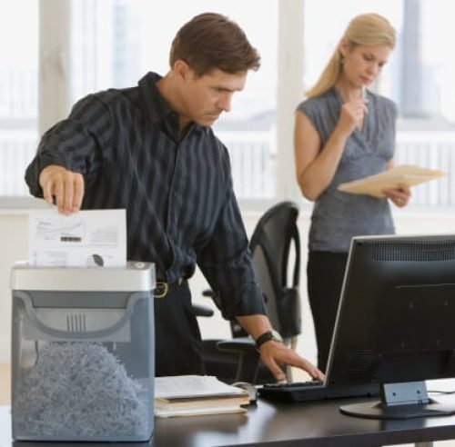 Man shredding documents in a traditional office paper shredder
