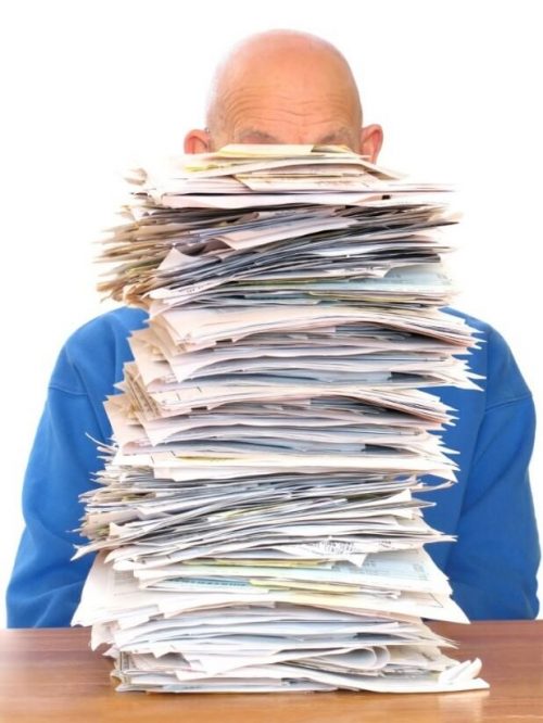 Pile of documents in front of a person sitting at a desk