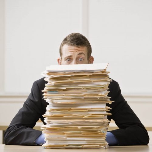Pile of documents in front of a person sitting at a desk