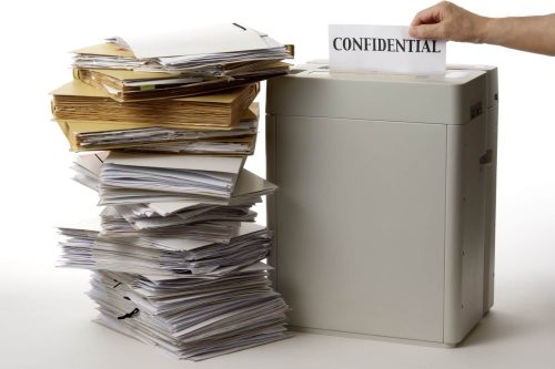 A stack of paper beside a shred bin